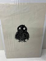Front view of the block print on cream paper wrapped in protective plastic, showing the complete bird image.