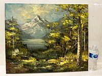 Full view of the oil painting displayed next to a water bottle for size reference, showcasing forest, mountain, and lake landscape.