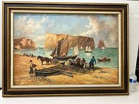 Full view of the framed oil on canvas painting showing a coastal beach scene with boats, horses, and fishermen in front of large rock cliffs.