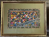 Full view of framed watercolour depicting a colorful village scene with many figures, houses, and flowers.