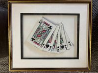 Framed artwork showing fanned playing cards with a gold frame and double mat