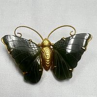 Front view of gilded butterfly pin with dark green carved jade wings on white background.