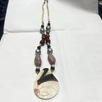 Full view of the entire handmade natural stone beaded boho style necklace laid flat on white background showing pendant, beads, and cord.