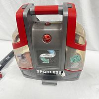 Front view of Hoover Spotless Pet Portable Cleaner showing handle, integrated water tanks, and branding.