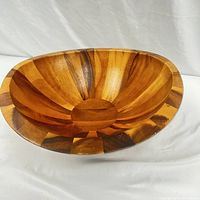Front and top view of the large wooden Nambe Bella salad bowl showing the wood grain and sunburst pattern.