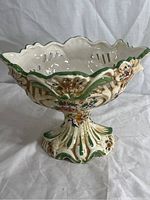 Full side view of vintage Capodimonte porcelain centerpiece bowl showing scalloped rim, pierced sides, floral decoration, and green accents on base.