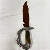 Close-up of the fighting tool showing the rusted blade, metal guard with engraving, and wood handle portion