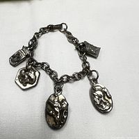 Full view of the vintage silver tone charm bracelet showing chain and five attached charms with lion and medallion motifs.