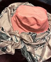 Pink bucket hat resting on top of a large patterned silk scarf.