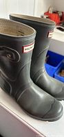 Black Hunter short rain boots with visible scuffing and creasing, size 7. Buckle strap on left boot is slacked with missing metal piece.