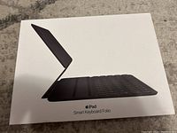 Photo of the white packaging box with an image of the Smart Keyboard Folio partially open, showing its slim design and keyboard layout.