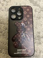 Top-down photo of the iPhone 13 Pro case front showing the cutouts for camera and flashes, the design of Robot Bear and patterned brown background.