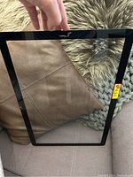 Black bezel replacement glass screen held above a brown and grey textured fabric background