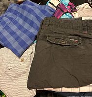 Several pairs of men's size 36 shorts laid out including blue checkered and olive green cargo style shorts.