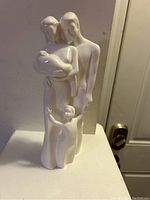Front view of white porcelain Coalport family statue with mother holding baby, father, and child.