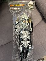 Front view of sealed packaging showing the full length of the Achmed window cling, including suction cup attached to the top.