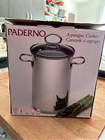 Front view of the box showing the Paderno brand and product name 'Asparagus Cooker' with an image of the stainless steel pot with lid.