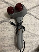Front view of Sharper Image handheld electric back massager showing two rounded red massage heads and attached power cord