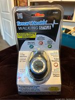 Front photo showing SmartHealth Walking Style watch in clear plastic packaging, text highlighting automatic tracking, step count, calorie burn, pulse reading.