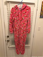 Full view of the pink onesie hanging showing fox print, hood, and zipper.