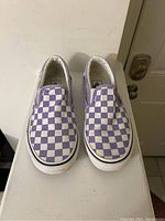 Front view showing the pair of Vans slip-on shoes with purple and white checkered pattern.