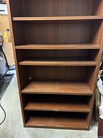 Front view of one wall shelf unit showing multiple adjustable wood veneer shelves and particle board construction.