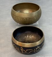 Two Tibetan brass singing bowls side by side showing exterior and interior details