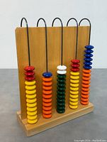 Front view showing colorful beads and five rods in wooden frame.