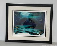 Full view of framed artwork showing underwater scene with two manatees and fish, black frame and white matting.