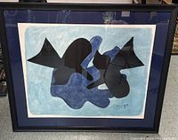 Framed print showing the full artwork inside black frame with blue mat and artist signature.