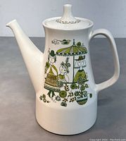 Front angle showing the coffee/teapot with handle on right and spout on left featuring folk art style figures and floral design.