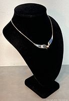 Necklace displayed on black bust showing design and styling.
