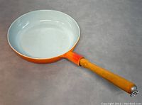 Top and inside view of the vintage cast iron enamel frying pan showing the pale interior and wooden handle