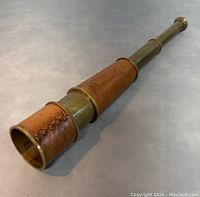 Fully extended view of three-section brass telescope with leather wrap and visible patina