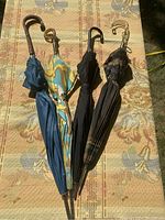 Four closed vintage umbrellas laid side by side showing canopy colors and handle styles.
