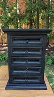 Front view of the commode showing five panel drawers with ring pull handles and black painted finish.