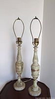 Pair of two onyx baluster style table lamps shown front-facing on a wood table.