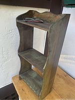 Full view of antique wooden wall shelf showing three-tier design with curved side panels and old finish.