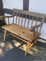 Front side angle showing the pine slab seat and maple turned legs and spindles of the bench.
