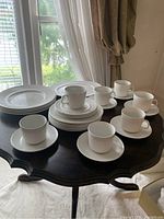 Full lot on dark wood table near window showing cups, saucers, plates, and platters in Athena ironstone pattern with ribbed design.