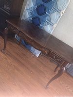 Full view of the wooden desk showing cabriole legs, three drawers, and overall design.