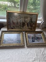 Three framed prints on a white surface in front of a window showing Croatian historical scenes in different styles and sizes.