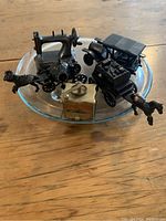 Photo showing all five die cast vintage item pencil sharpeners on clear round glass dish with wooden table background.