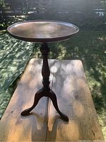Full view of the tripod side table showing round wooden top, turned pedestal, and three legs.