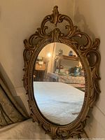 Front view of the oval gilt pressed wood Rococo style mirror showing overall condition and design.