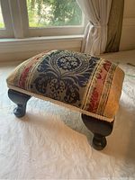Footstool displayed on fabric, showing entire item and design