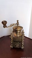 Full side view showing the entire coffee grinder including handle, base, and ornate pillars