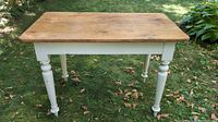Front view of antique pine work table showing the full rectangular two-board top and white painted turned bottle style legs.