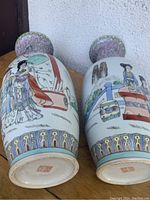 Photo showing pair of 18 inch tall Chinese porcelain vases with detailed enamel decoration and traditional scenes, including people and intricate borders.
