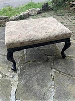 Photo showing the full vintage stool with floral brocade upholstery and Queen Anne style wooden legs on stone flooring.